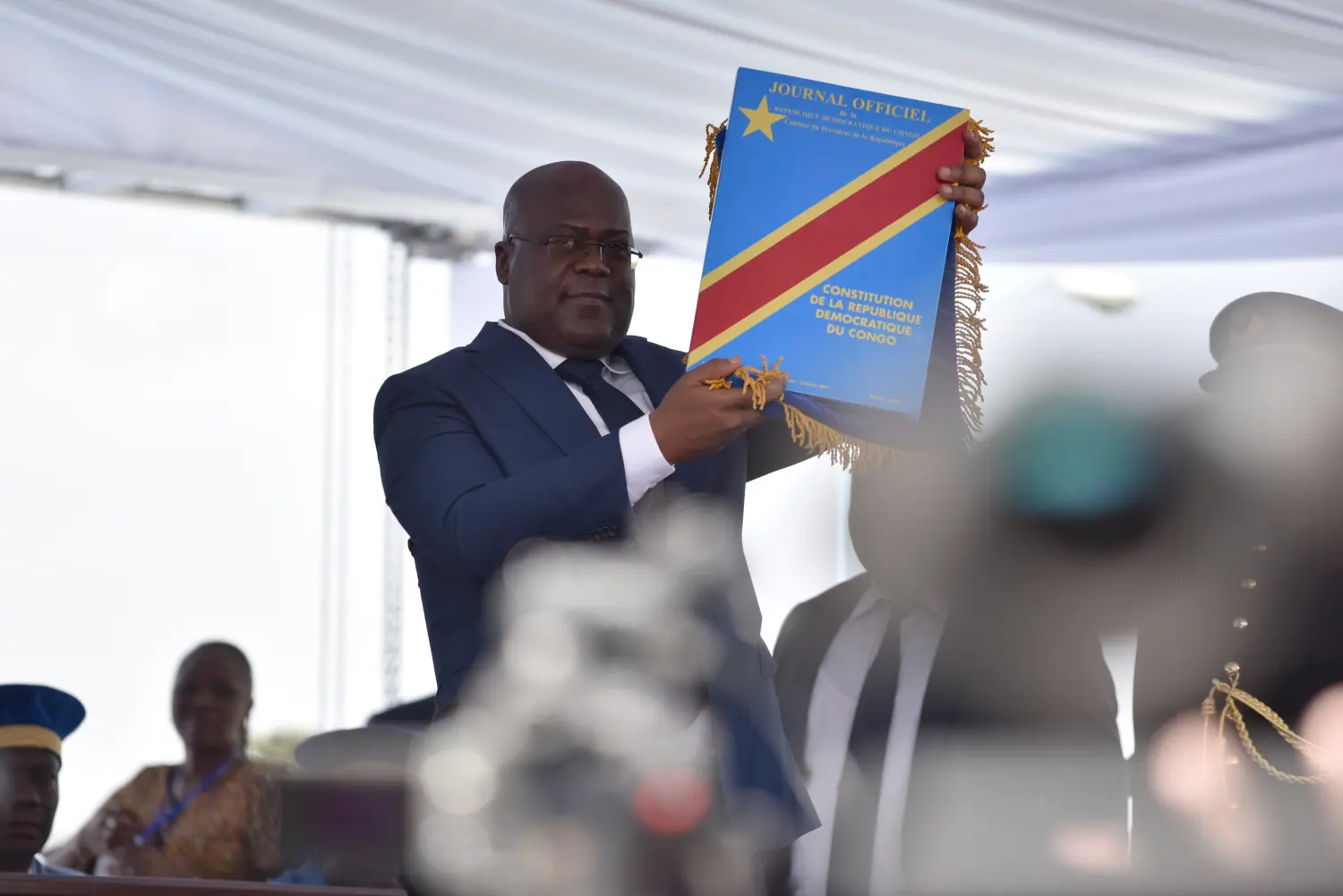 A political figure holds up the official constitution of the Democratic Republic of Congo during a formal event